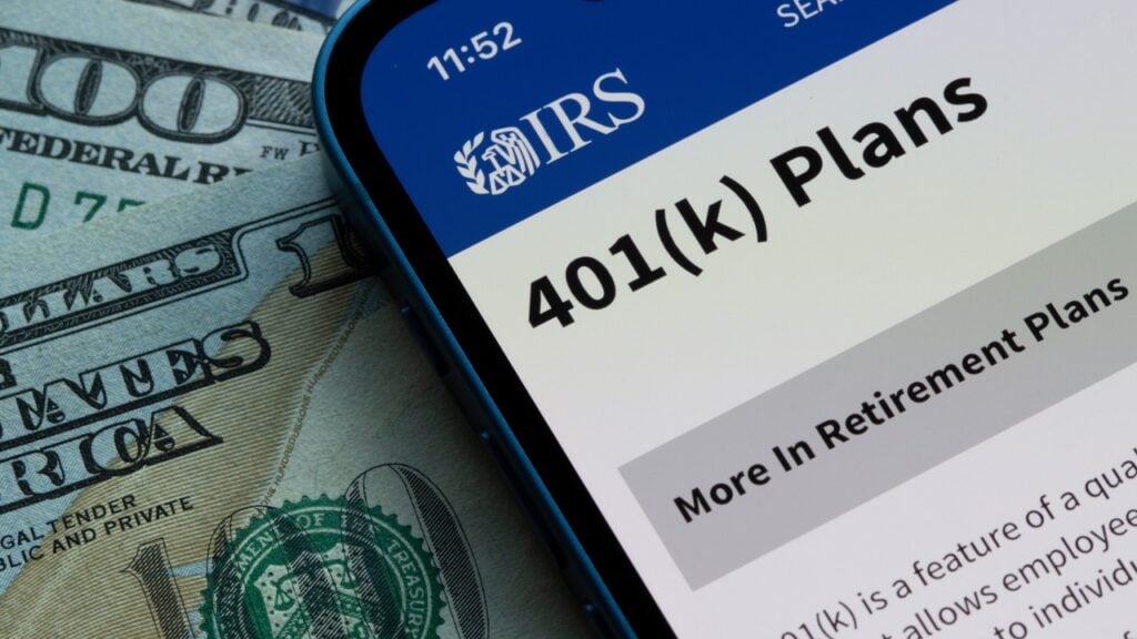 The IRS website with 401k plans and money behind the phone.