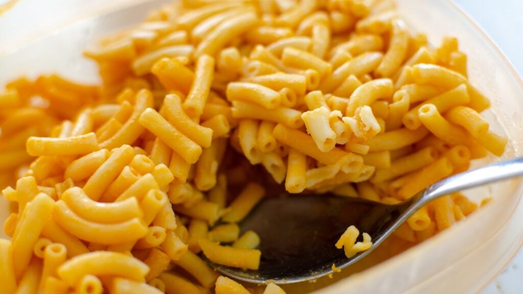 A bowl of mac and cheese with as spoon.