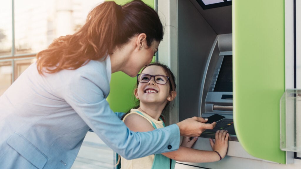 mother and daughter at ATM with debit card