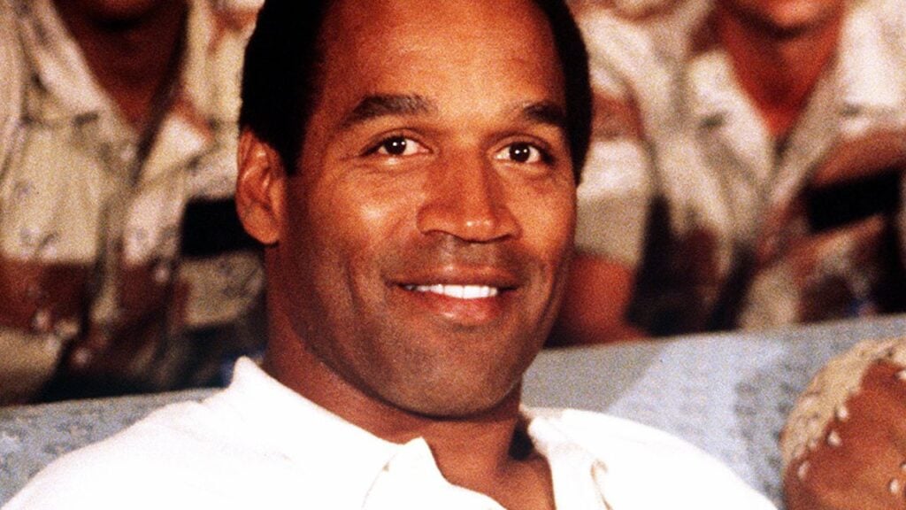 NBC Sports commentator and former professional football player O. J. Simpson sits with a group of servicemen to watch a Thanksgiving Day football game. Simpson is visiting U.S. troops who are in the region for Operation Desert Shield.