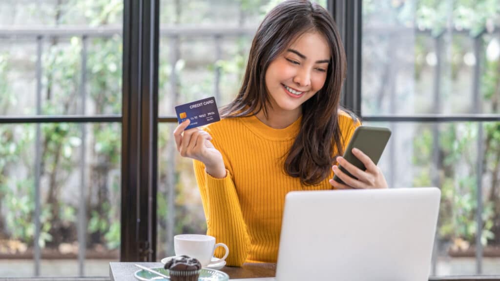 woman using credit card and mobile phone for online shopping