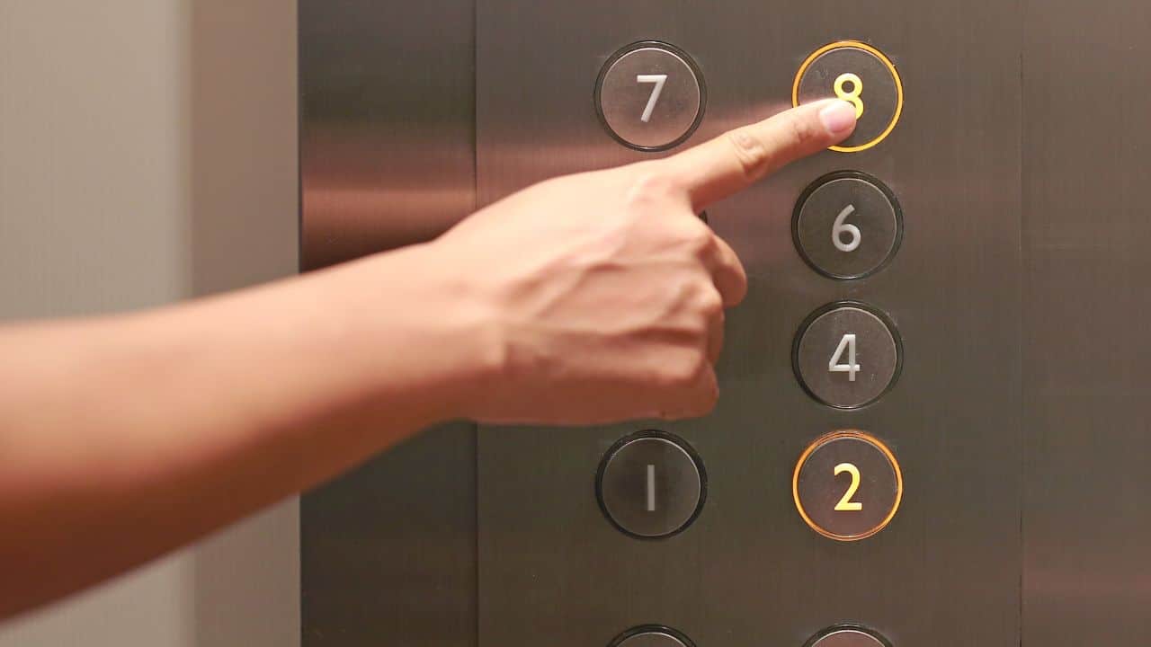 Forefinger pressing the eighth floor button in the elevator